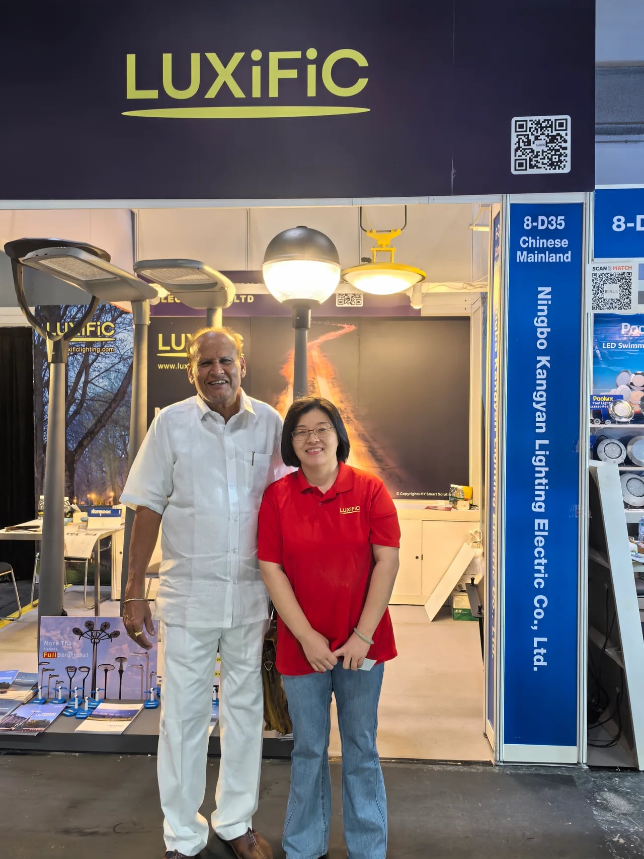 A visitor and team member at the LUXiFiC stand with street and landscape luminaires